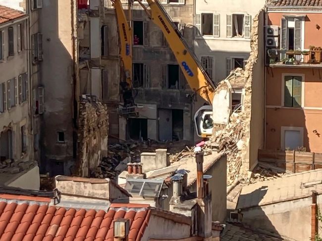 V troskách zrútenej budovy zomrelo najmenej šesť ľudí. Nasadenie psov skomplikoval požiar